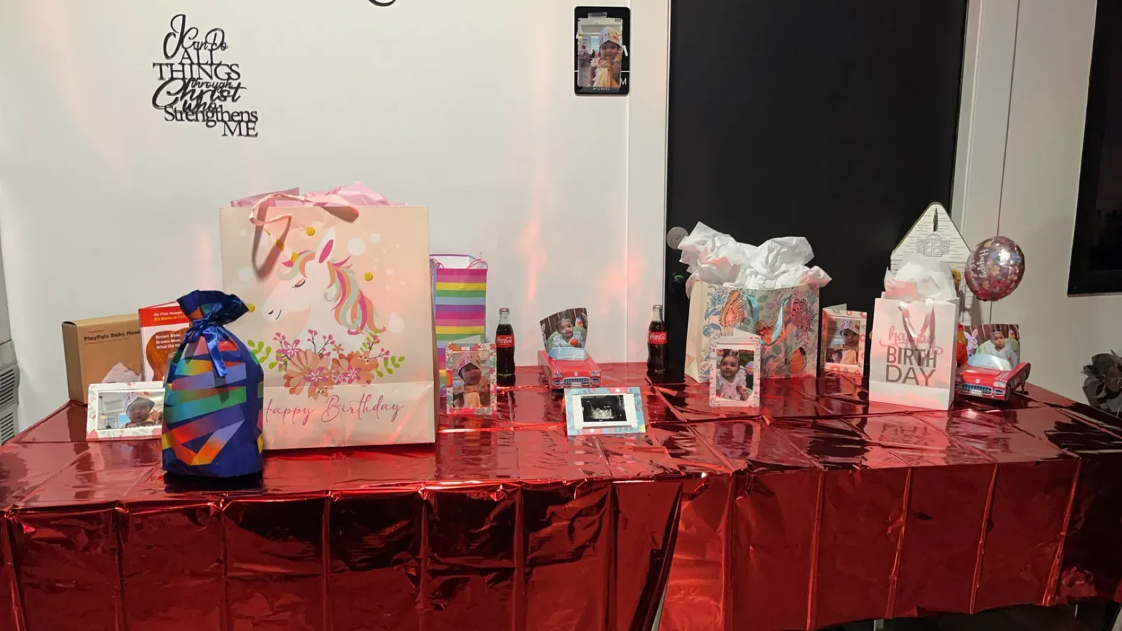 Birthday gifts and framed family photographs arranged on red linen