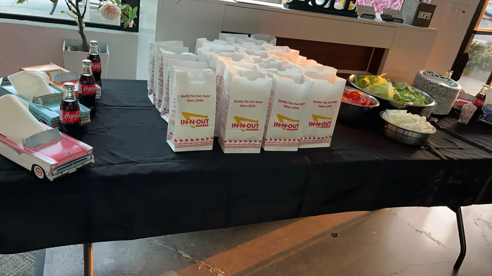 Buffet with individual meal bags, fresh salad, bottled soda, and vintage car accents