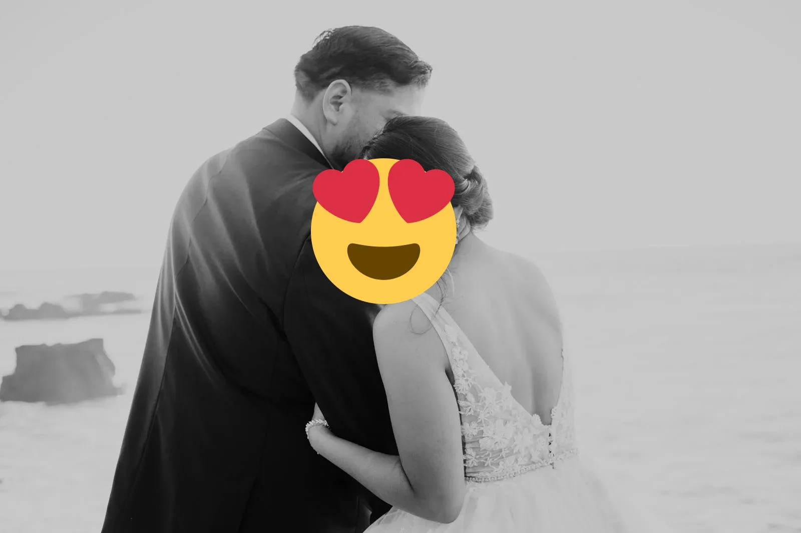 A black and white portrait of a wedding couple embracing by the ocean