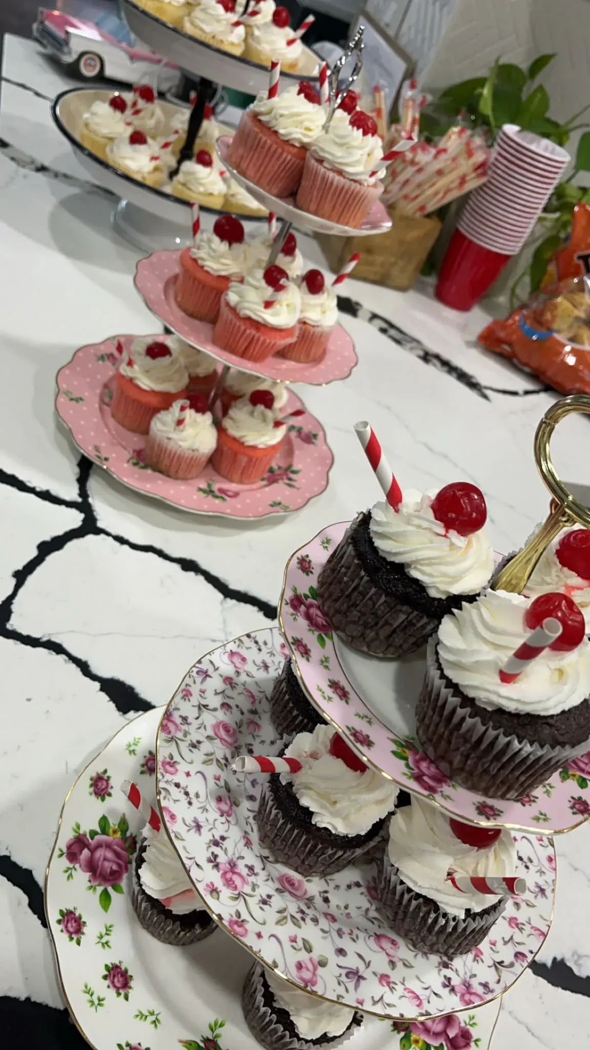 Cupcakes topped with cherries and arranged on vintage floral tiered stands