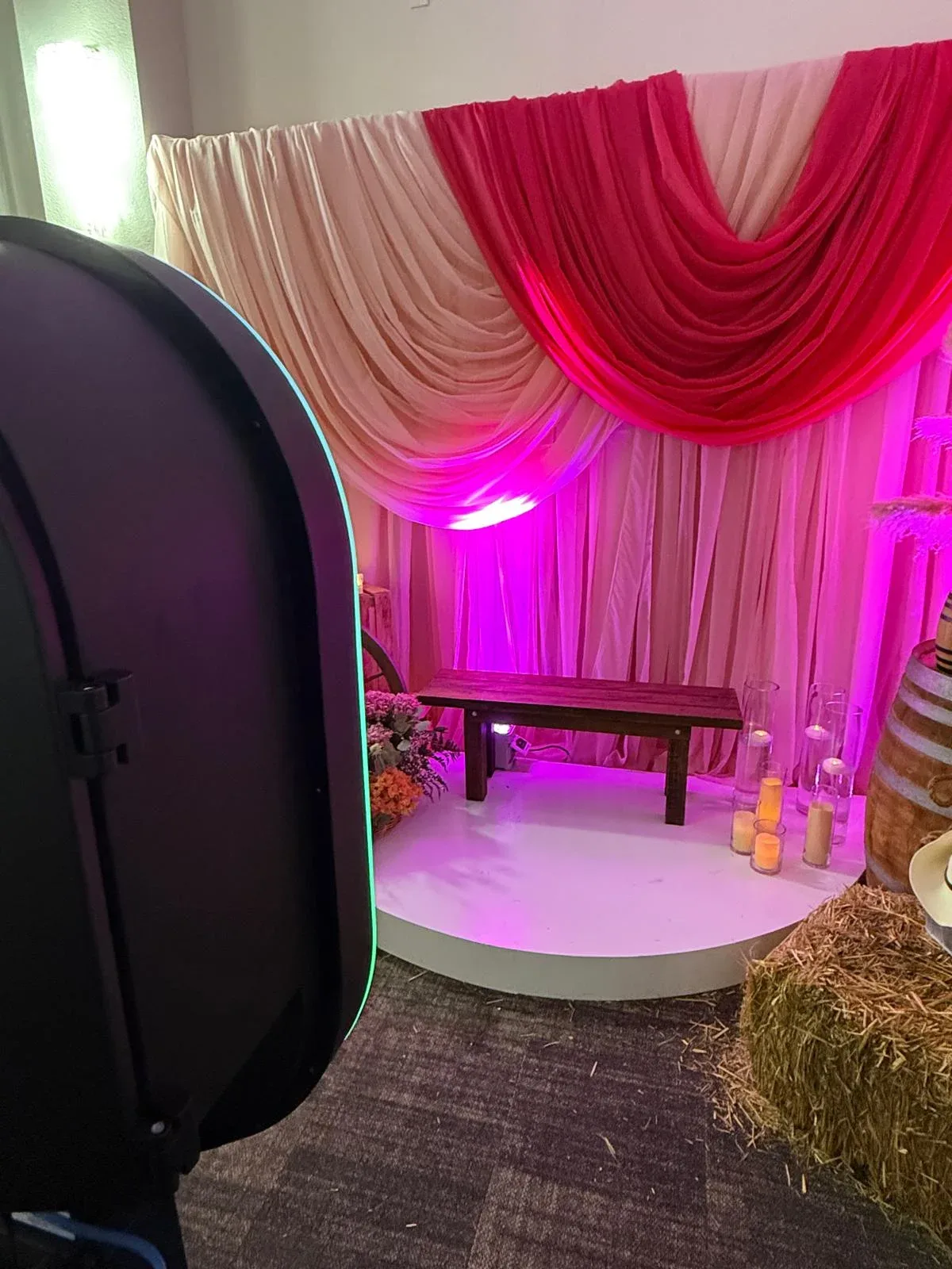 Pink and ivory draping with purple lighting behind a white photo platform