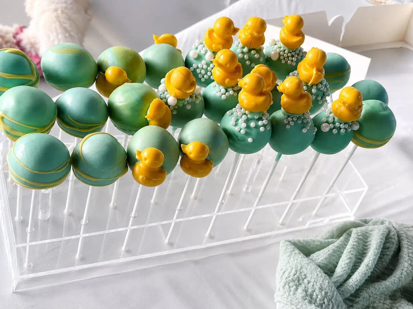Mint green cake pops finished with yellow ducks and pearl sprinkles