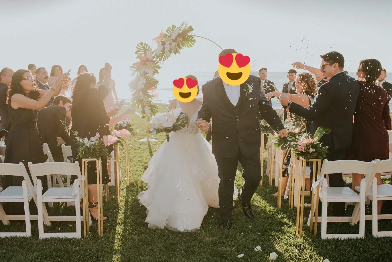 A couple walking between rows of white ceremony chairs in a sunlit garden