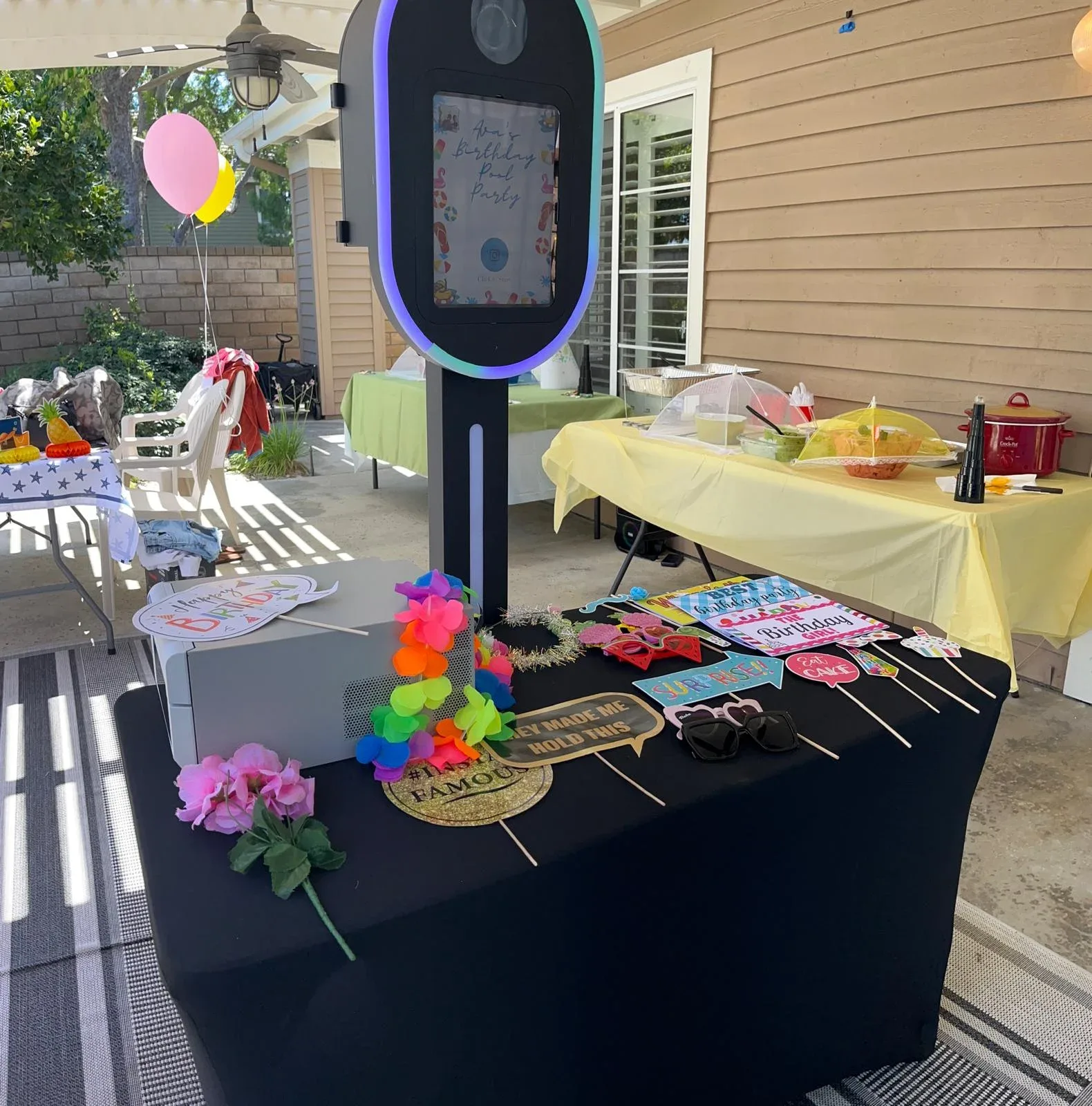 A garden photo booth with colorful props and pastel balloon decorations