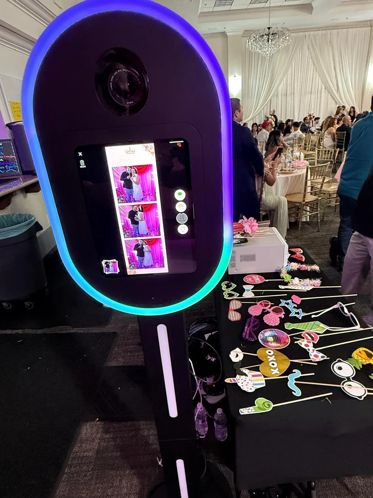 A photo booth with a glowing purple frame and a table of playful props