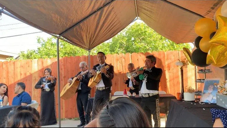 Musicians performing beneath a canopy beside a birthday balloon display