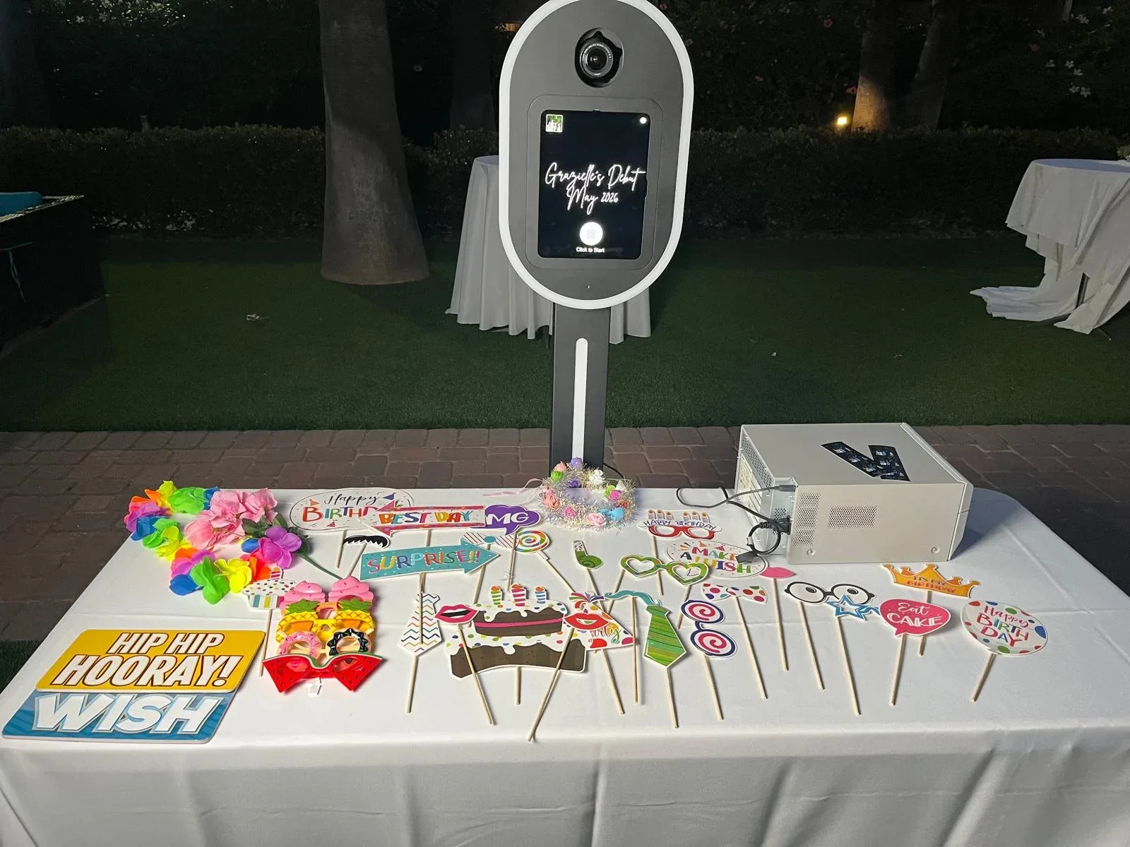 An outdoor photo booth with colorful props arranged on a white table