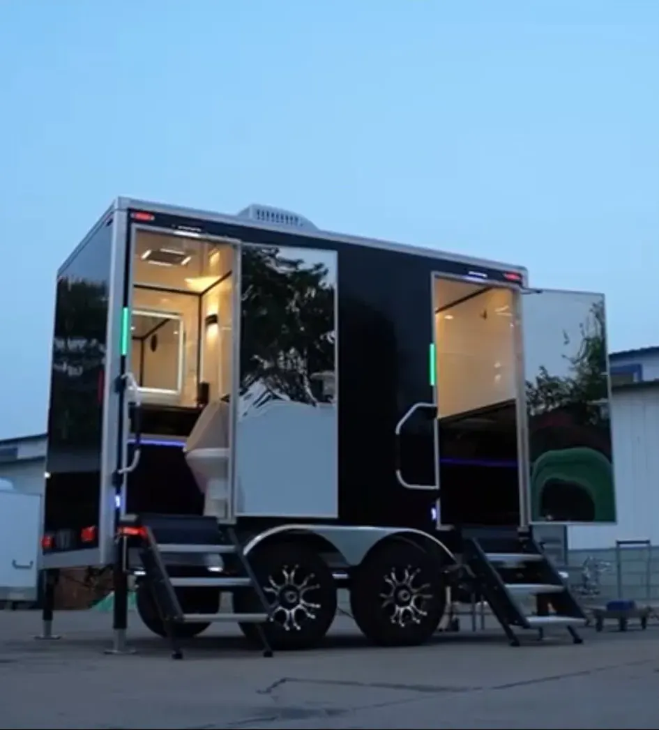 Black restroom trailer with two illuminated guest entrances at dusk