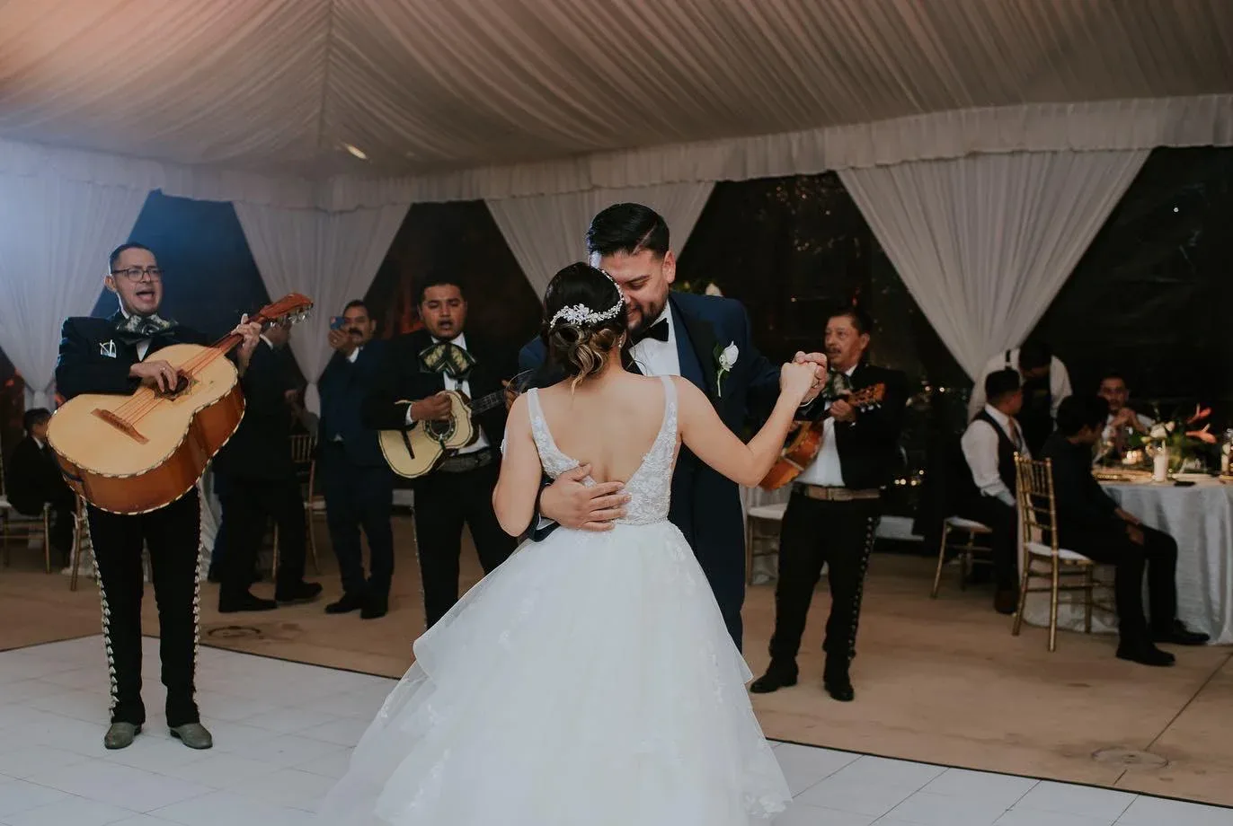 A wedding couple dancing in a draped room with live musicians